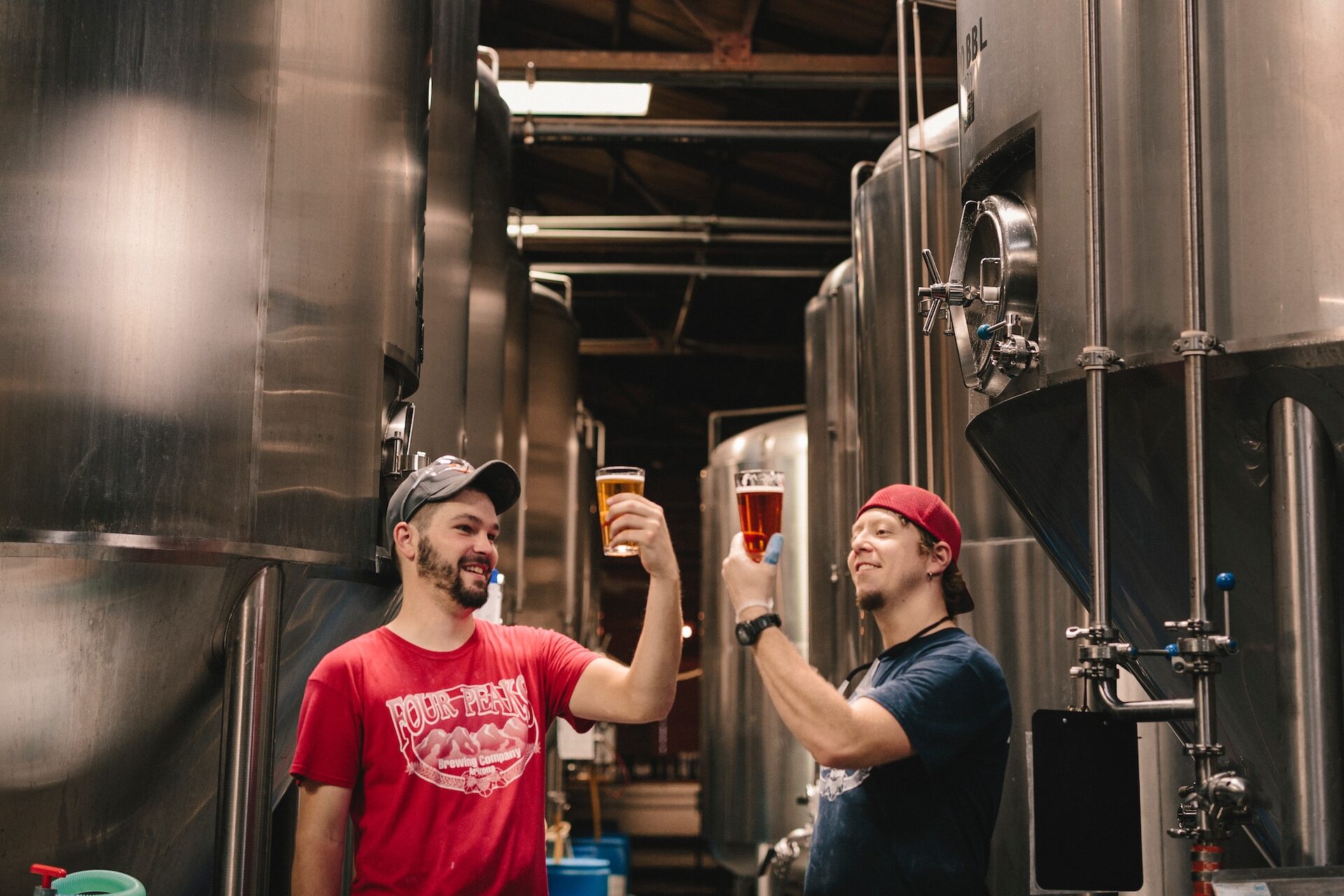 Two brewers in a brewery looking at pints